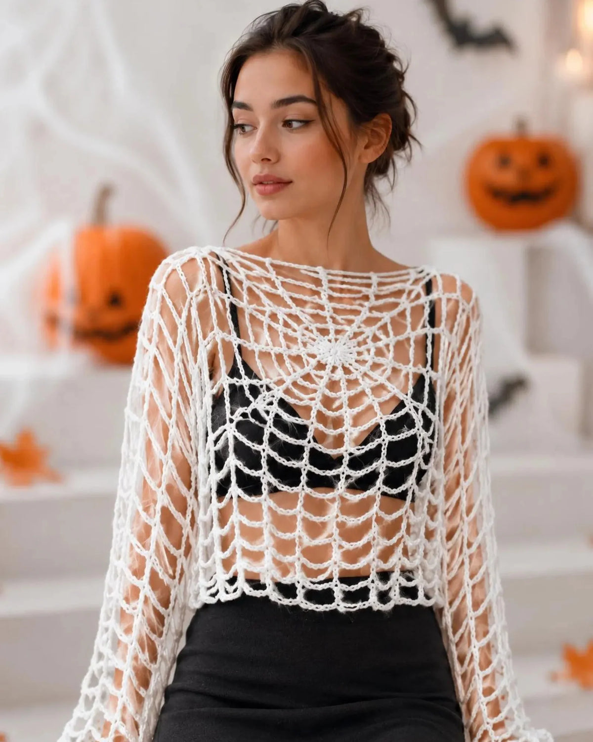 Black crochet spider web crop top with long flared sleeves worn over a tank