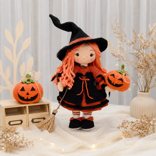Crochet witch doll Beatrix standing next to small crocheted pumpkins