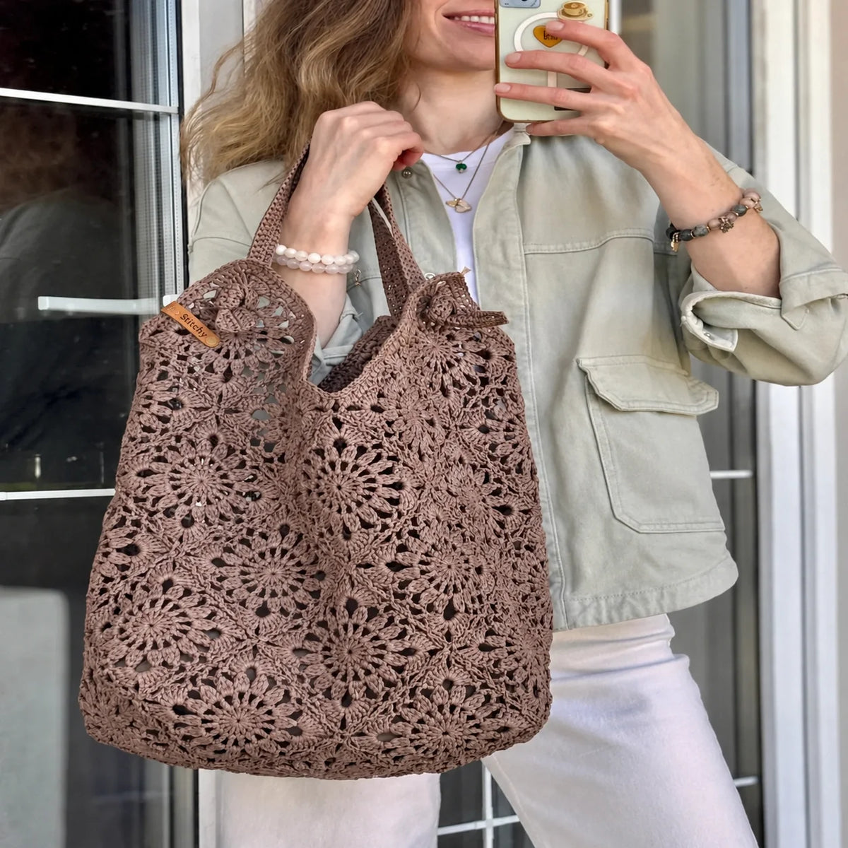 Roomy crocheted granny square tote filled with everyday items