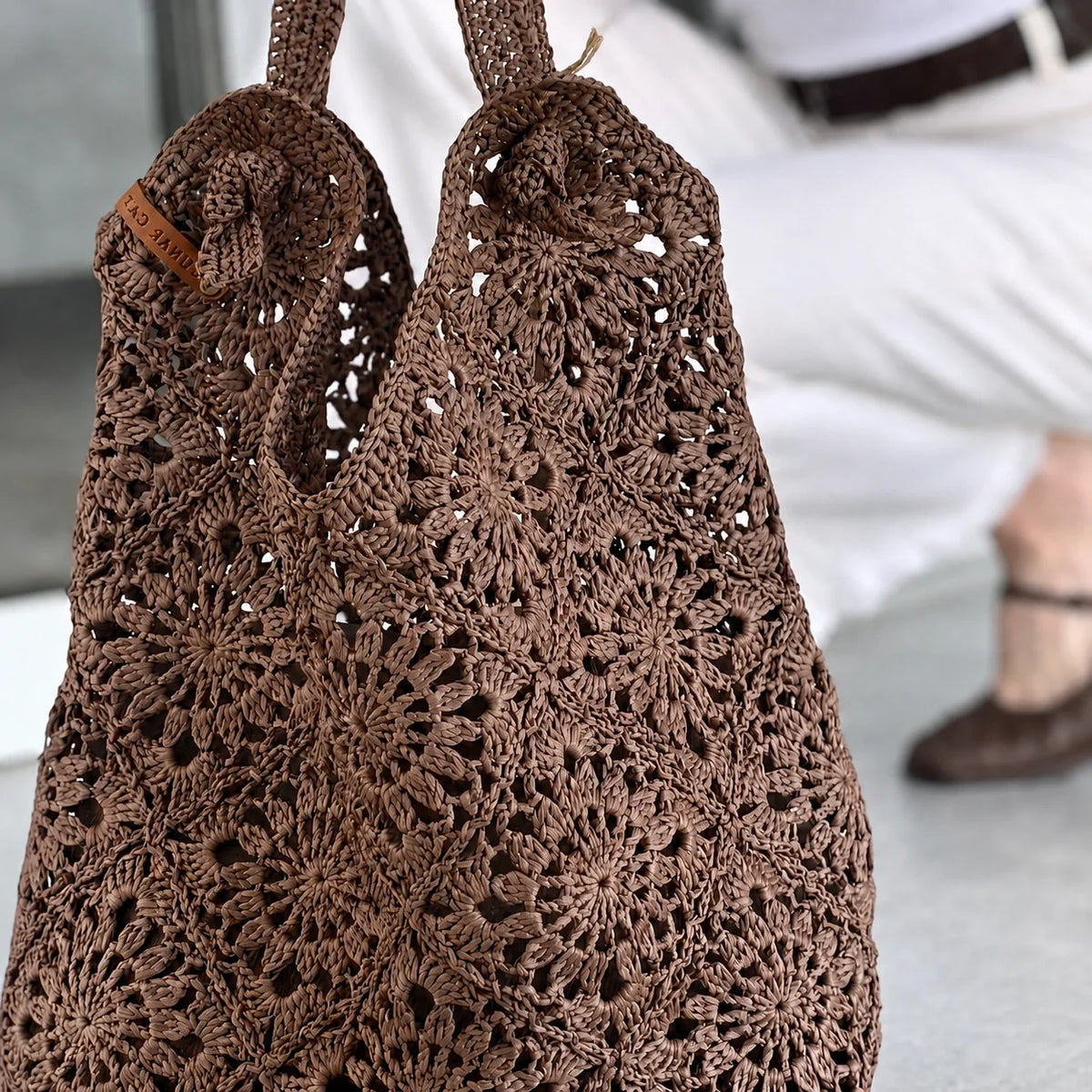Woman carrying a crocheted raffia granny square bag