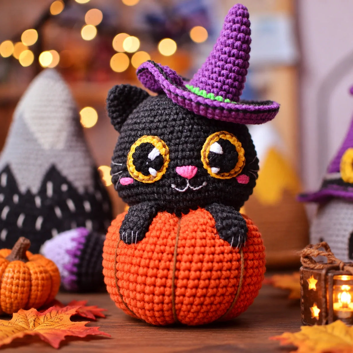 Crocheted black cat sitting in an orange pumpkin wearing a purple witch hat