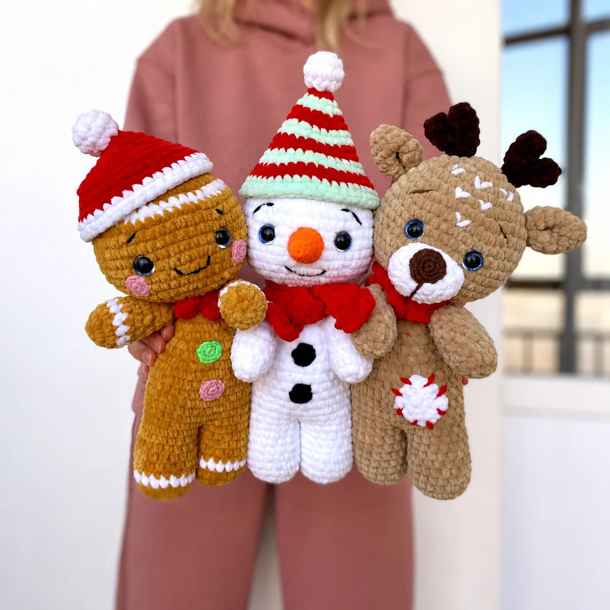 Crocheted reindeer, gingerbread man and snowman amigurumi trio displayed together as Christmas decor