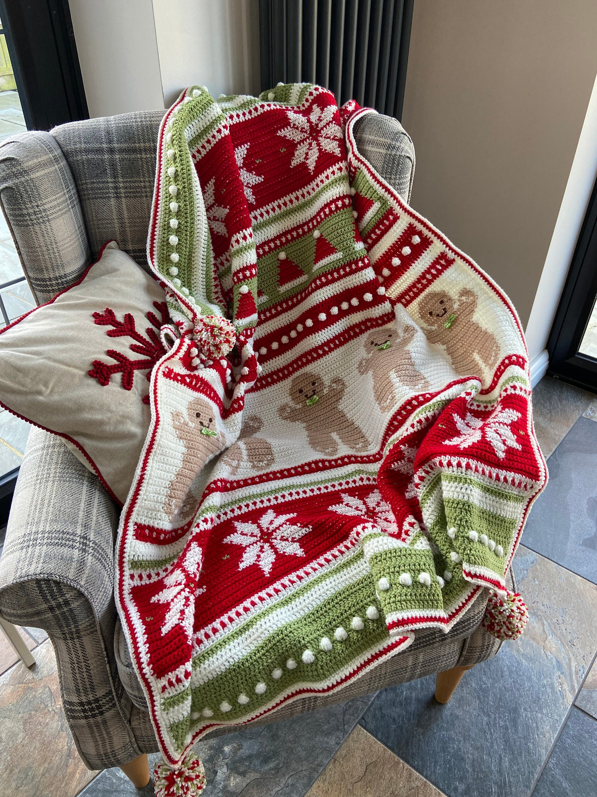 Christmas Eve Wishes blanket in red, cream and green on an armchair