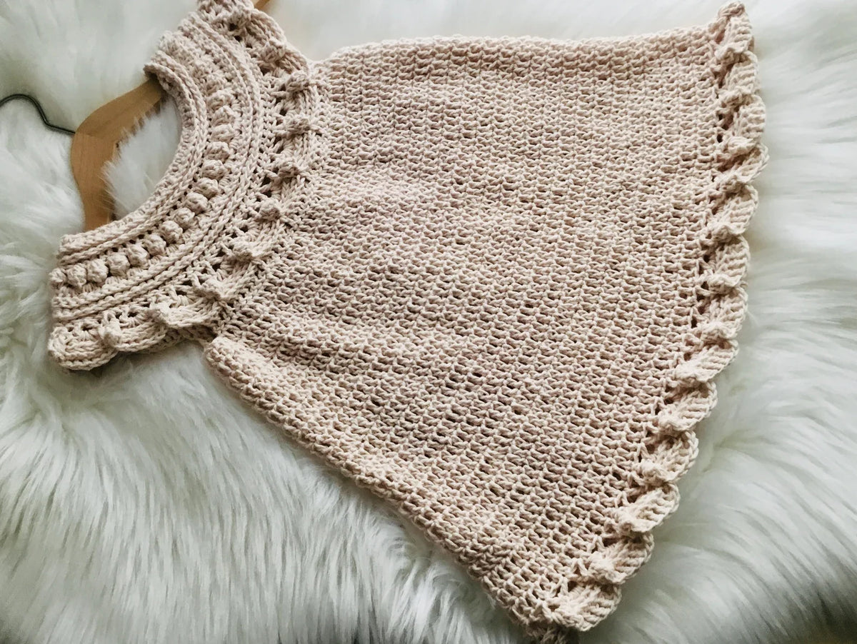 Handmade crochet baby dress laid flat