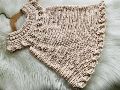 Handmade crochet baby dress laid flat