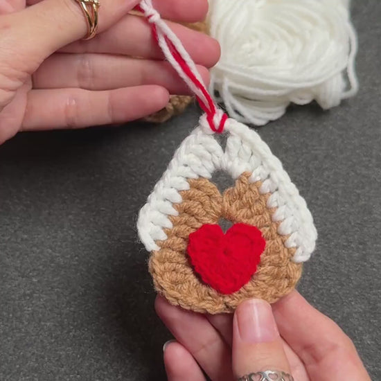 Crochet gingerbread house ornament hanging on a Christmas tree